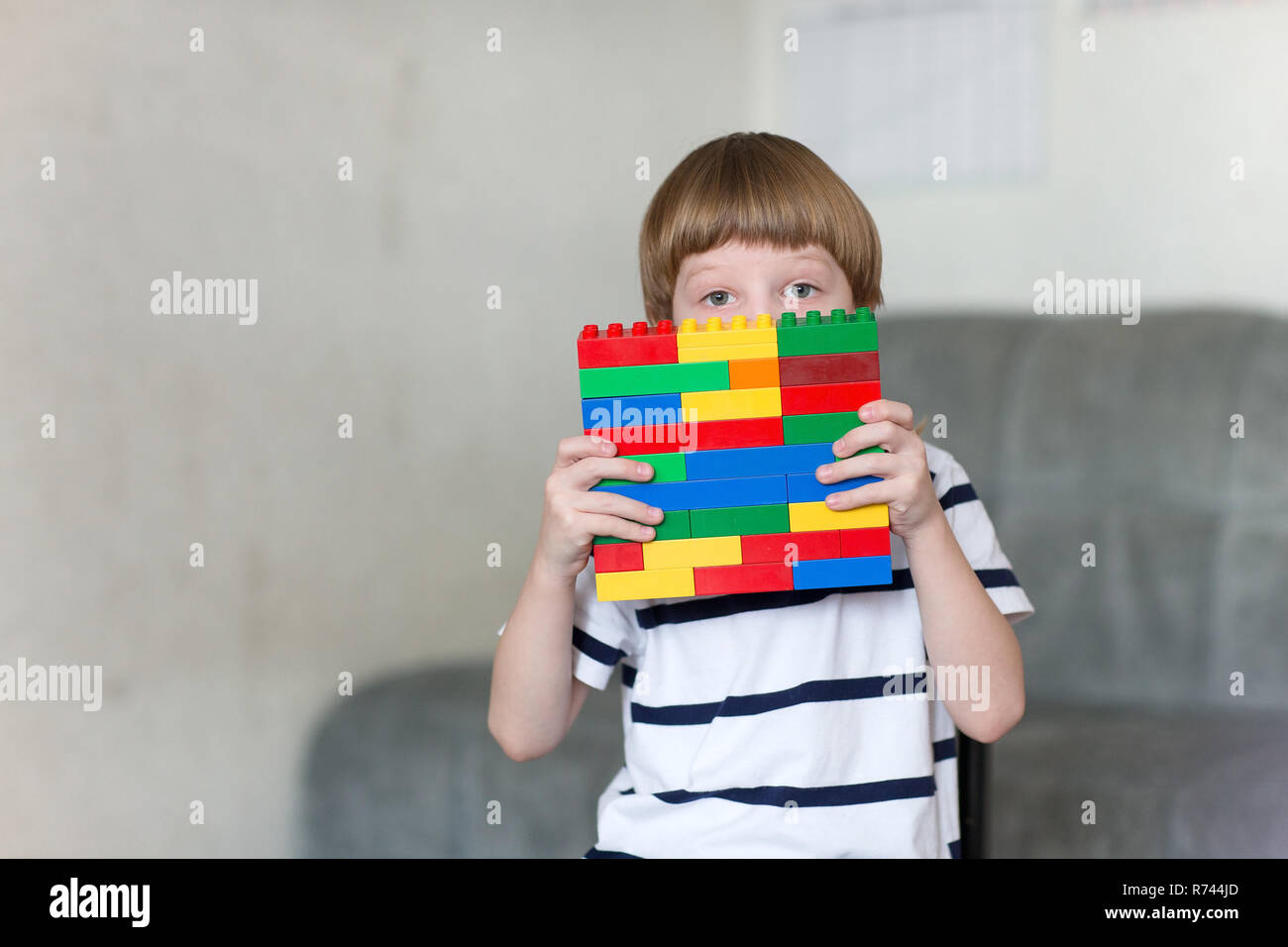 Little kid boy playing with lots of colorful plastic blocks indoor ...