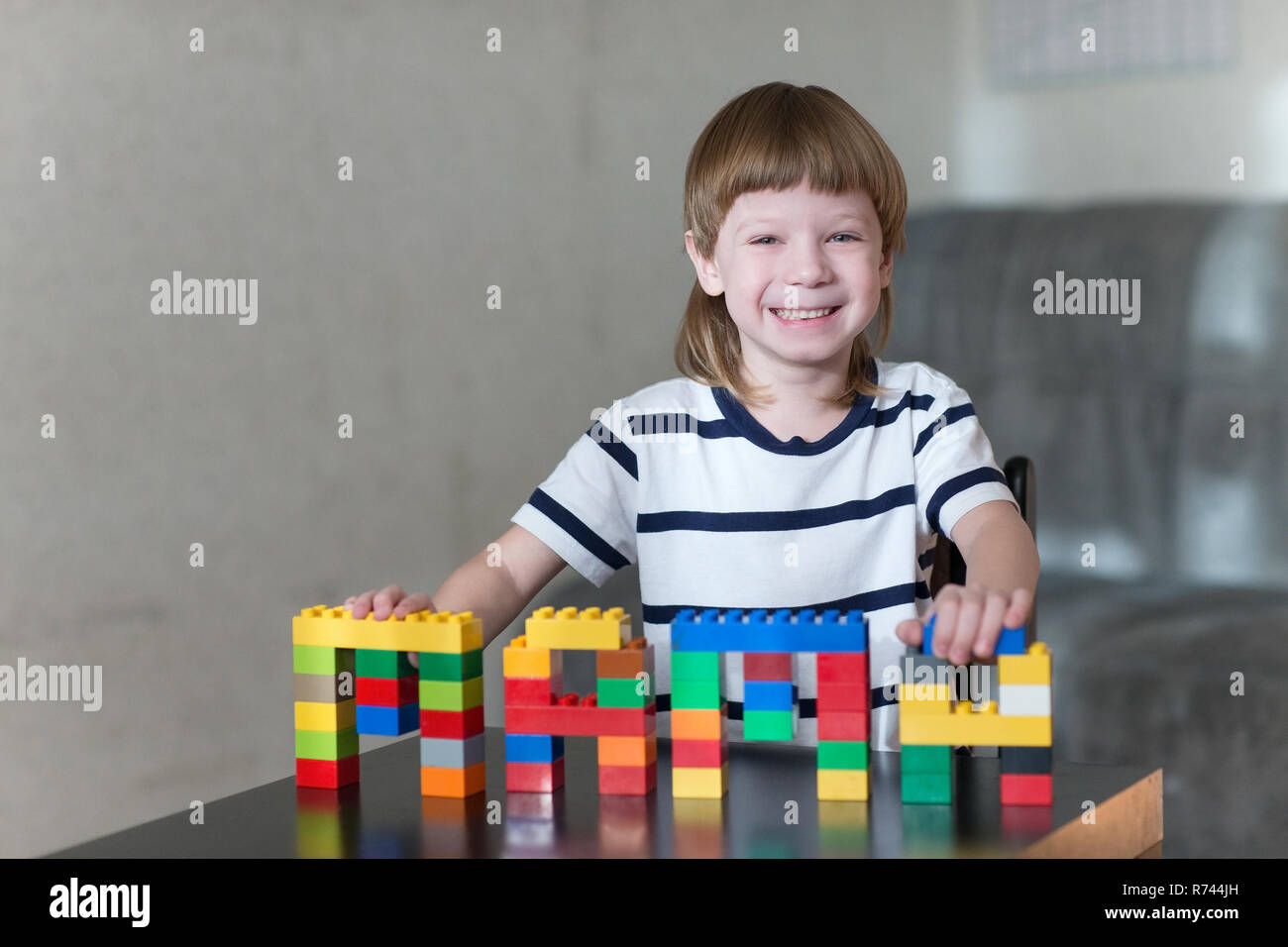 Little kid boy playing with lots of colorful plastic blocks indoor ...