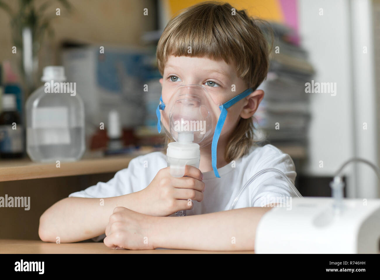 child holds a mask vapor inhaler. breathing through a steam nebulizer