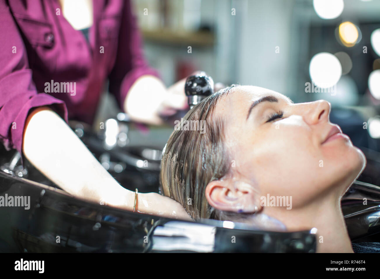 Hairdresser rinsing customer's hair in salon Stock Photo