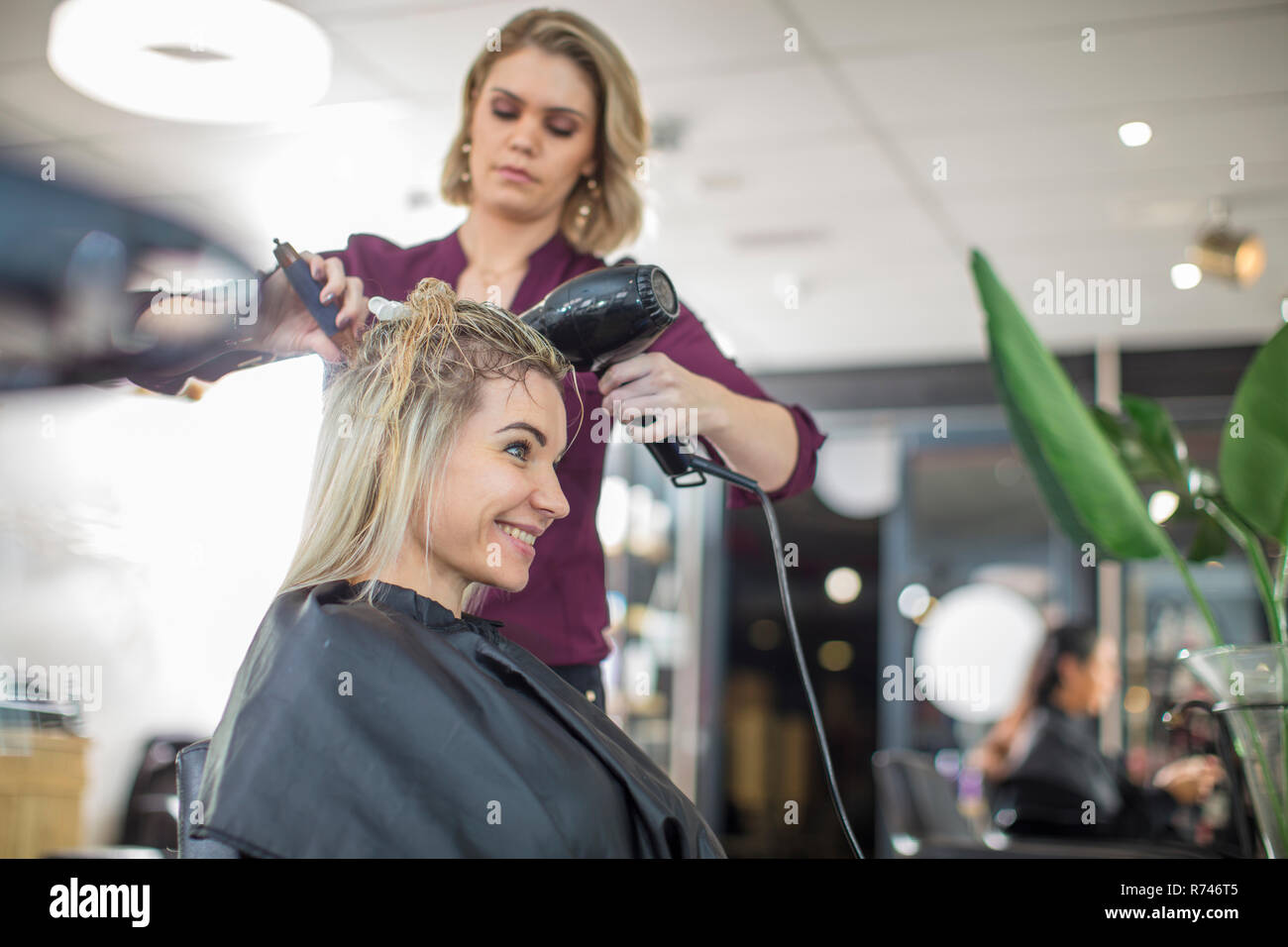 Hairdresser blow drying customer's hair in salon Stock Photo