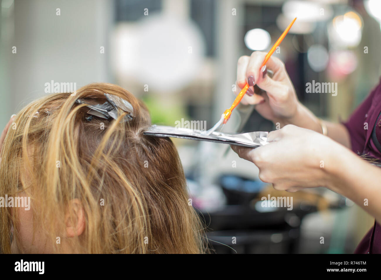 Hairdresser colouring customer's hair in salon Stock Photo