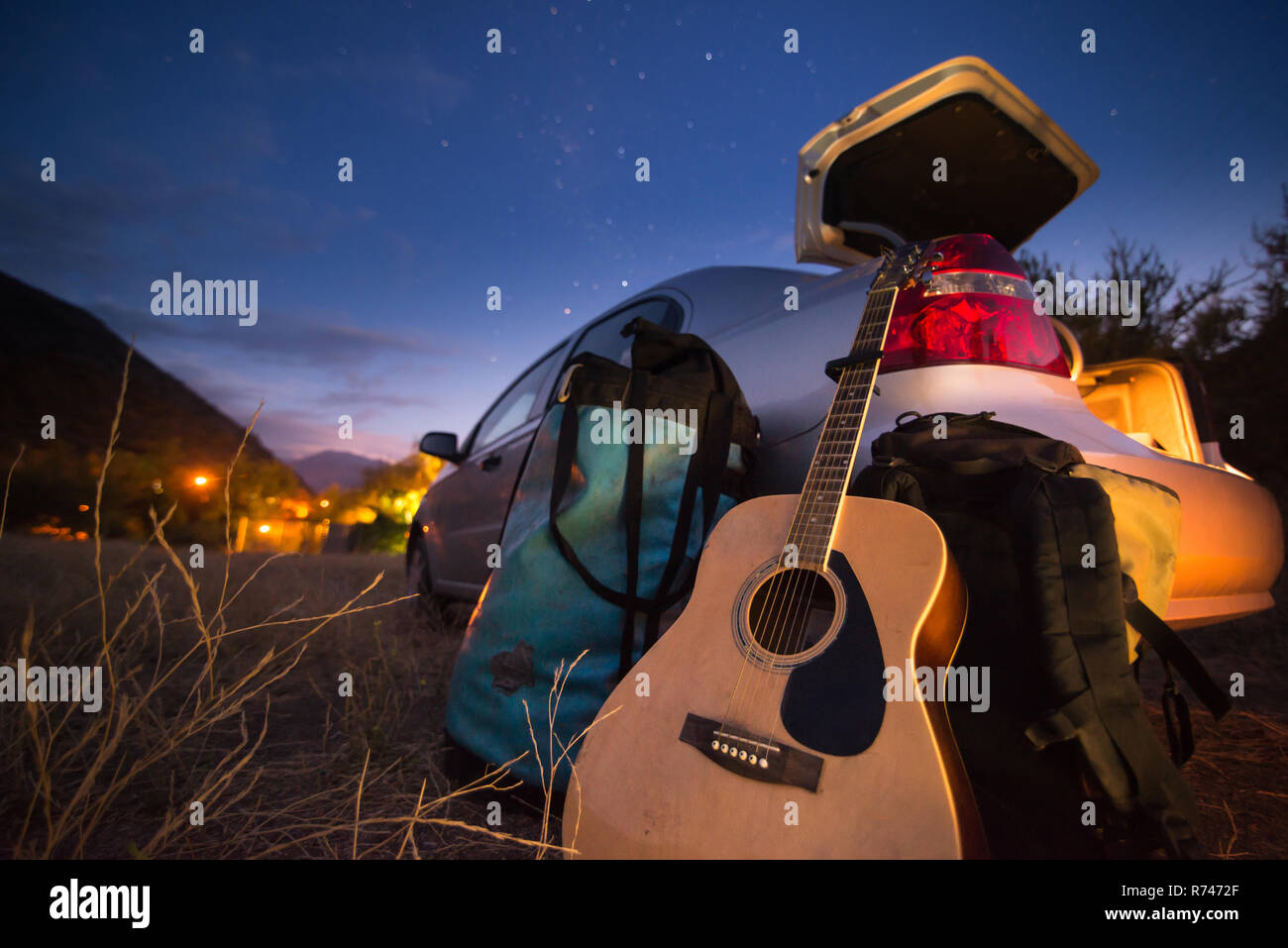 Guitar, backpack and luggage by car boot Stock Photo