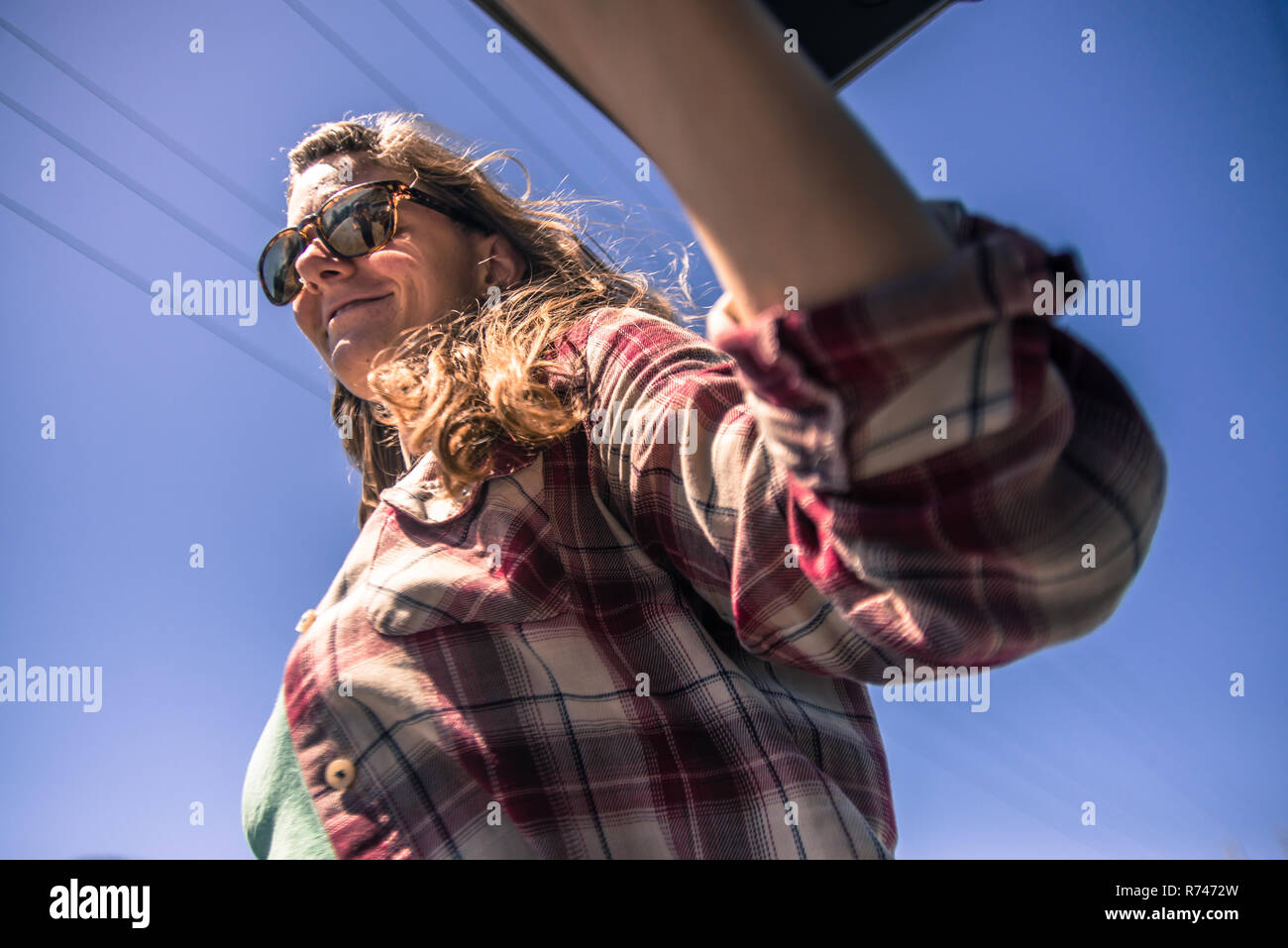 Young woman in sunglasses against blue sky, low angle view Stock Photo