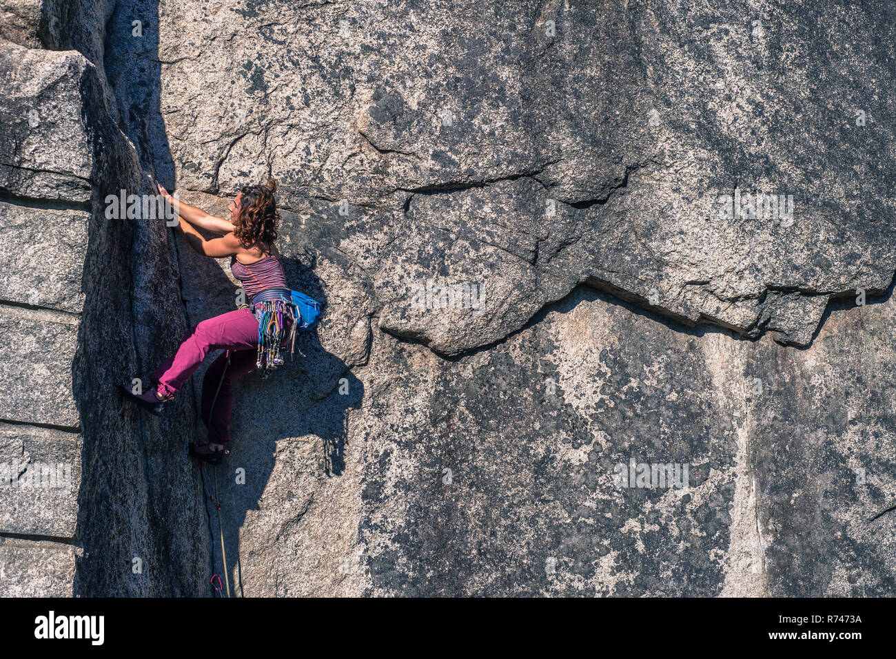 Young female rock climber climbing rock face, full length, side view, Smoke Bluffs, Squamish, British Columbia, Canada Stock Photo