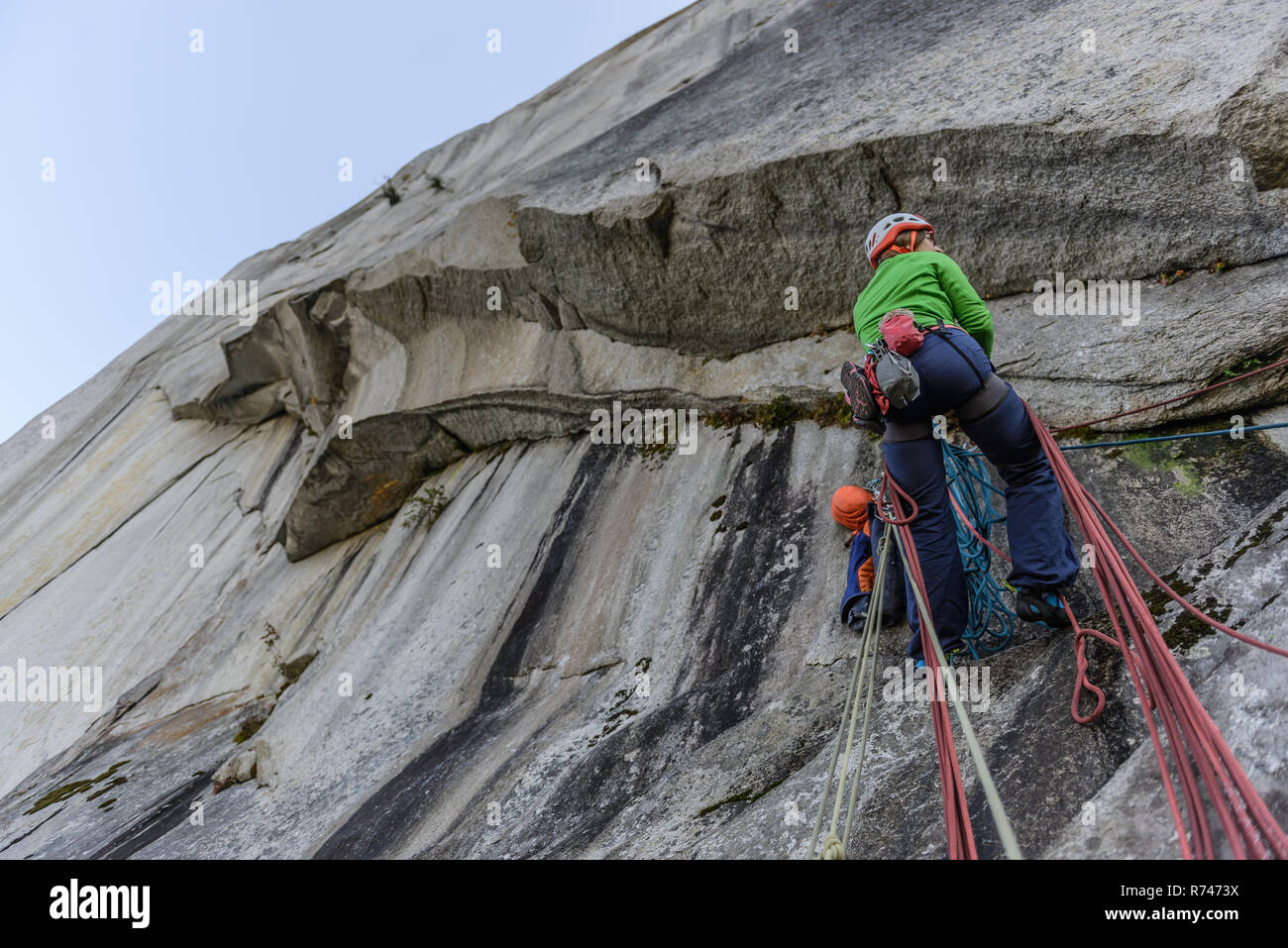 Young female rock climber climbing rock face, low angle view, The Chief, Squamish, British Columbia, Canada Stock Photo
