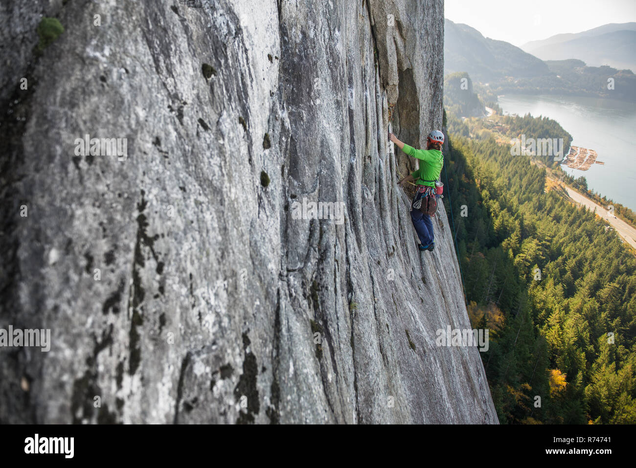 Young female rock climber climbing up rock face, elevated view, The