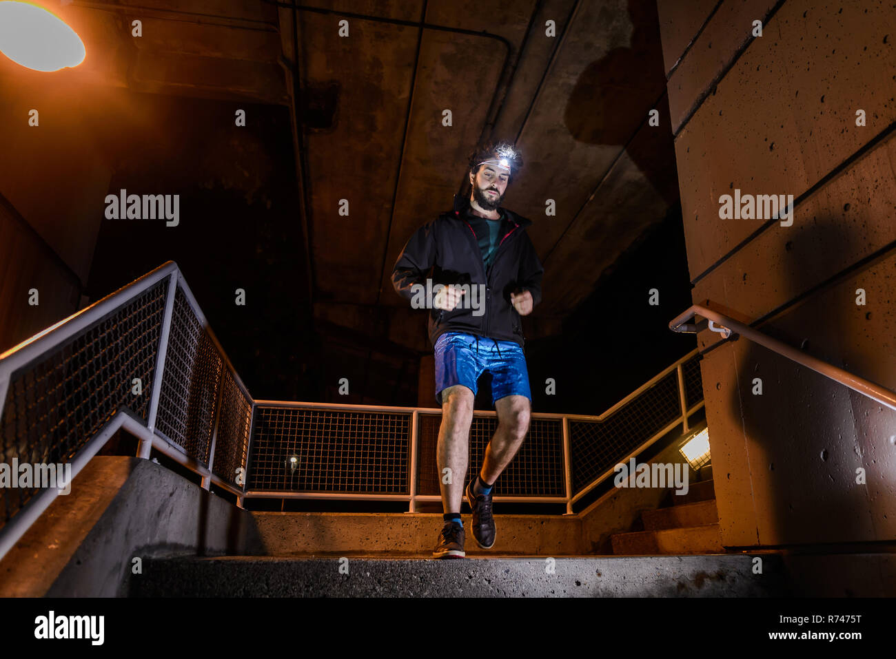 Runner with headlamp going down stairs, North Vancouver, Canada Stock Photo
