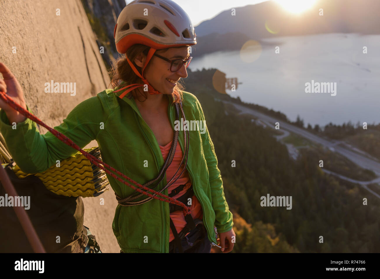 Young female rock climber looking down from The Chief at sunset, Squamish, British Columbia, Canada Stock Photo