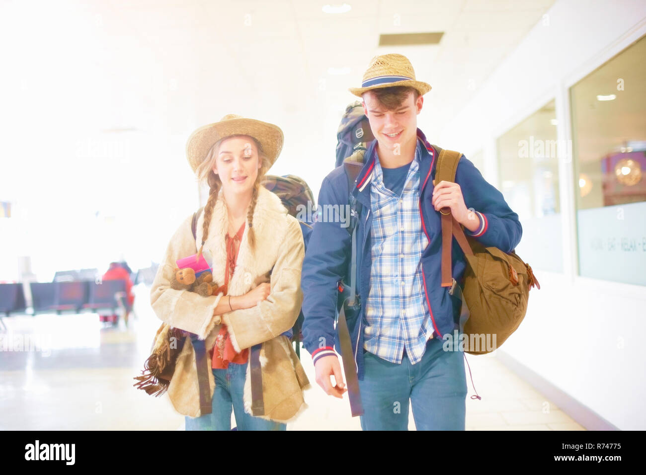 Young couple at airport, carrying backpacks, setting off on journey Stock Photo