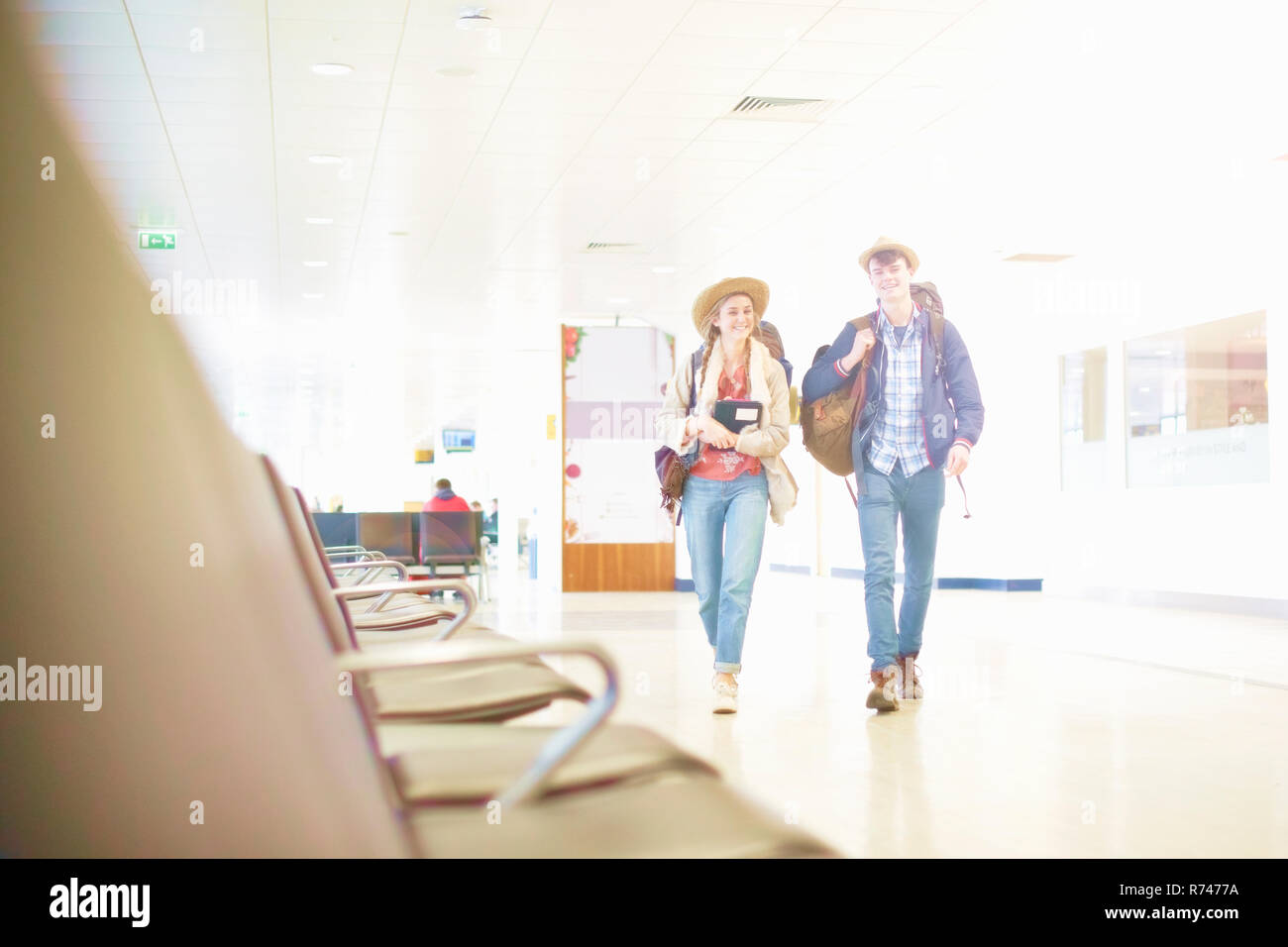 Young couple at airport carrying backpacks, low angle view Stock Photo