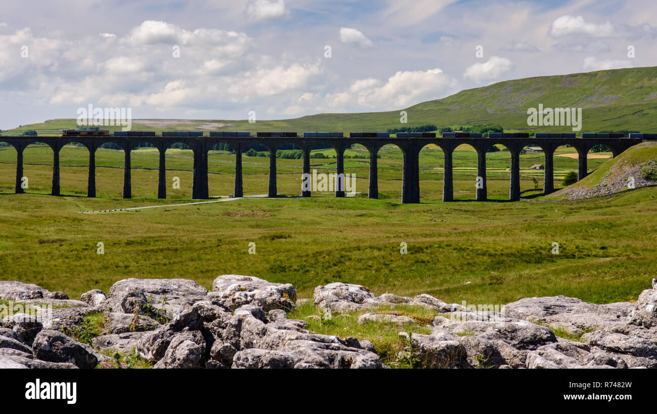 Ribblehead, England, UK - July 3, 2015: A train of freight containers crosses the Ribblehead Viaduct on the scenic Settle and Carlisle railway in Engl Stock Photo