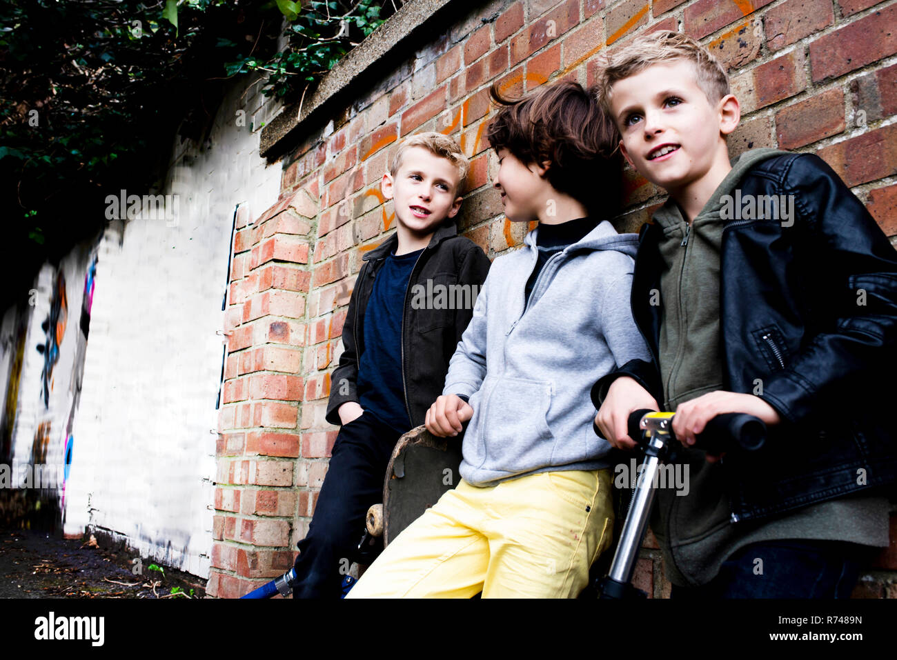 Boys leaning against brickwall Stock Photo