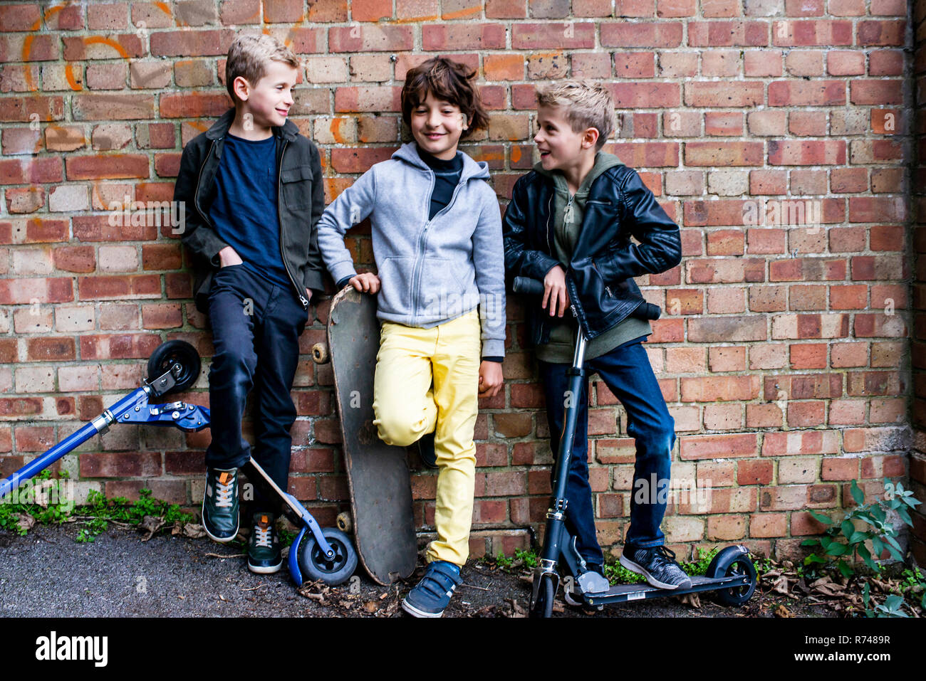 Boys leaning against brickwall Stock Photo
