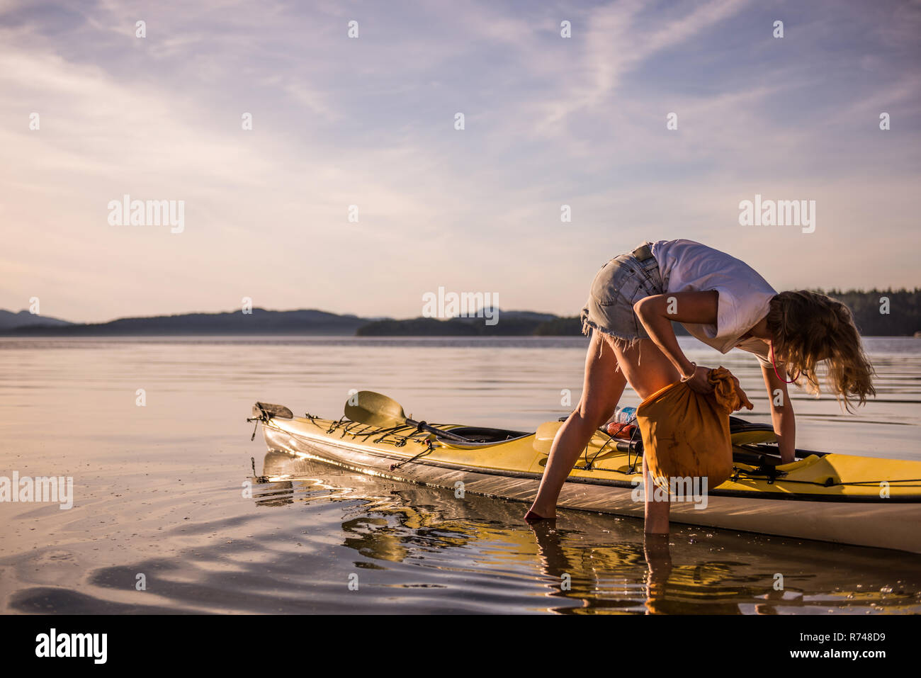 Young female kayaker unpacking kayak, Quadra Island, Campbell River