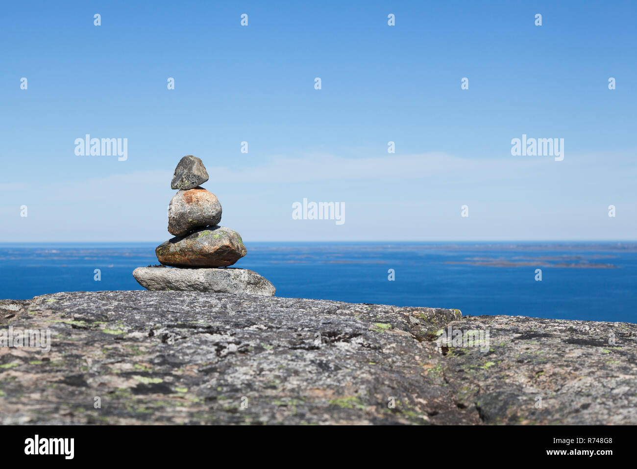 Cairn on top of rock formation with inlet and blue sky, Aure, More og Romsdal, Norway Stock Photo