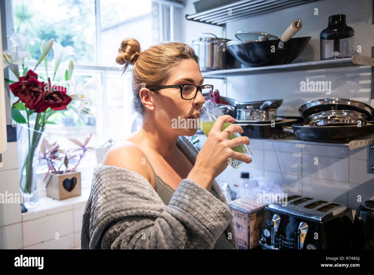 Pregnant mid adult woman drinking fresh juice in kitchen Stock Photo