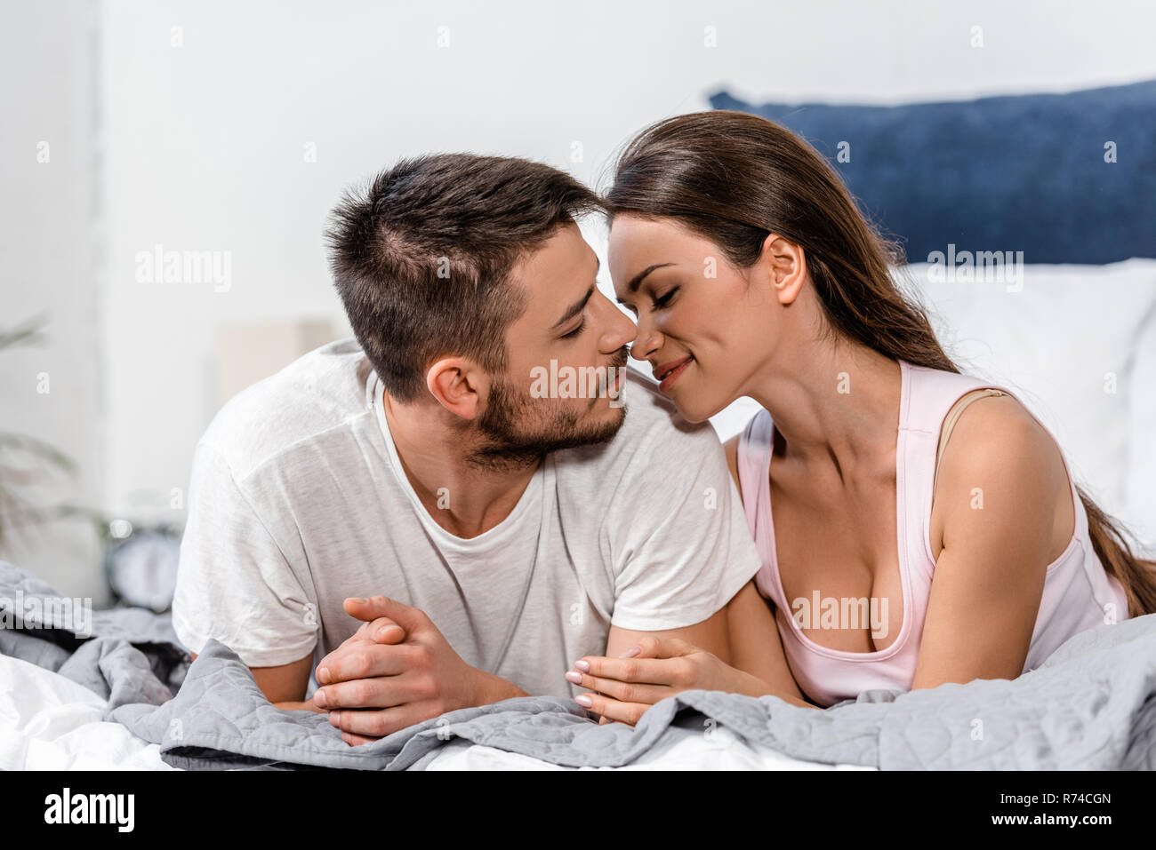 girlfriend and boyfriend in pajamas lying on bed and going to kiss in  morning in bedroom Stock Photo - Alamy