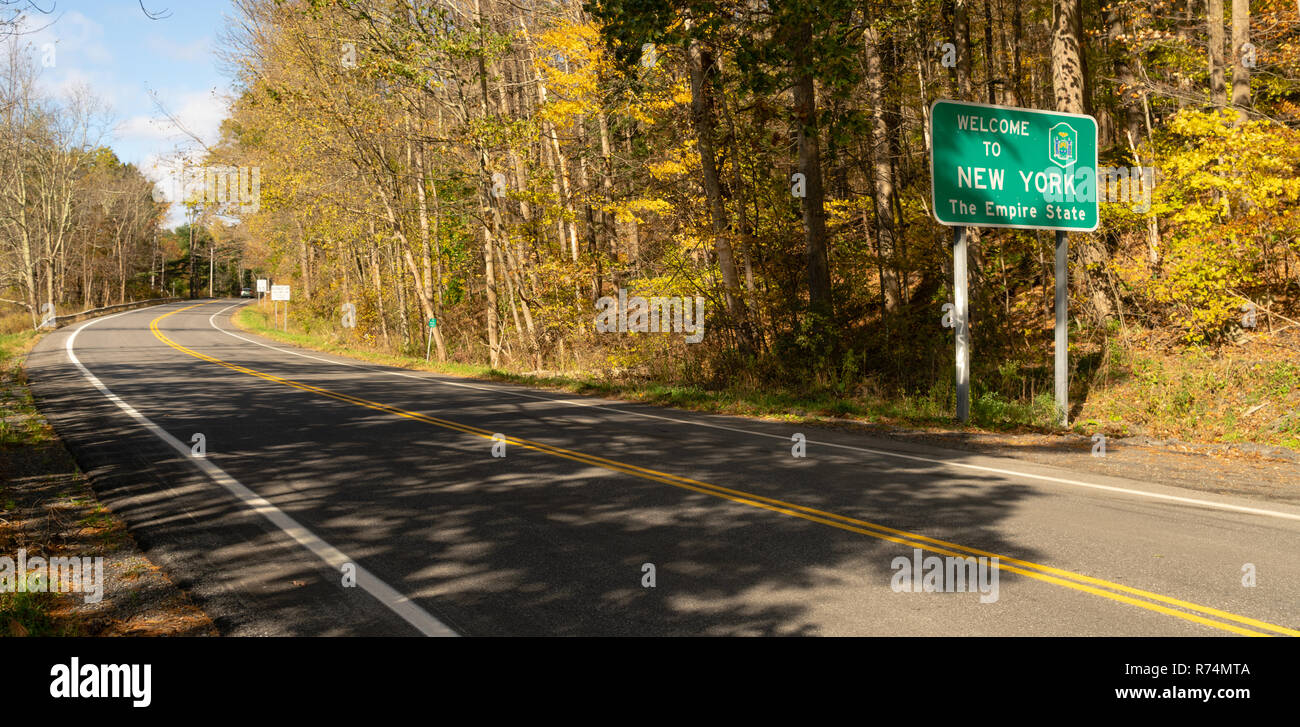 Beautiful seasonal fall color over the highway sign that welcomes travelers to New York Stock Photo