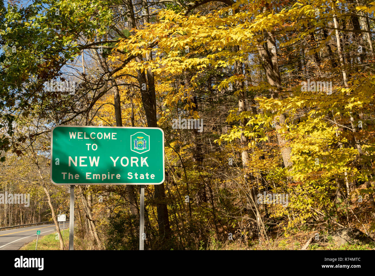 Beautiful seasonal fall color over the highway sign that welcomes travelers to New York Stock Photo