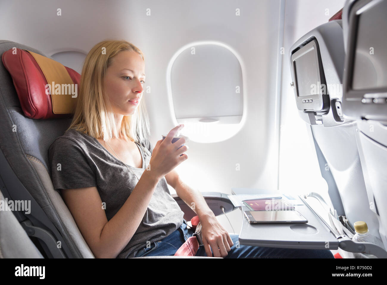 Woman drinking coffee on commercial passengers airplane during flight ...