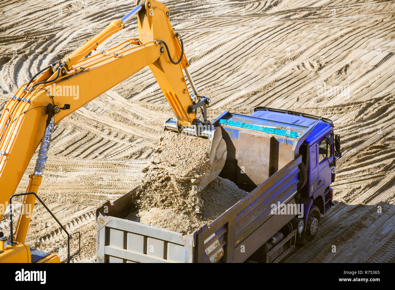 Work of the excavator and truck at a sand quarry. Excavator loading sand into a dump truck. Stock Photo