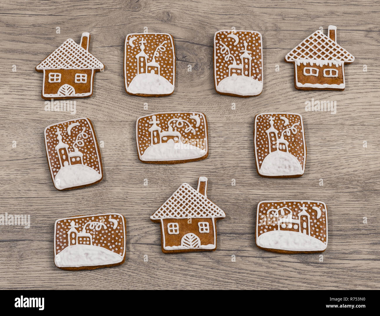 Group of ornate Christmas gingerbreads on wood background. Beautiful decorated gingerbread sweets in house shape and with hand-painted chapel in snow. Stock Photo