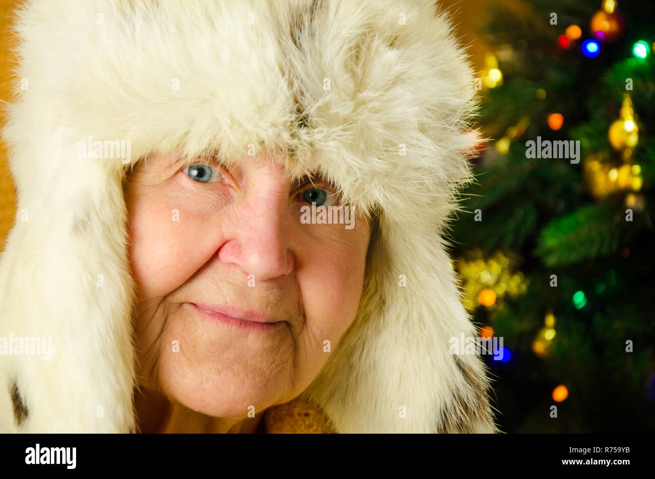 Positive senior female is expressing happiness in holiday. Portrait of happy grandmother over decorated New Year tree, merry Christmas concept, happy family, lifestyle indoor, Stock Photo