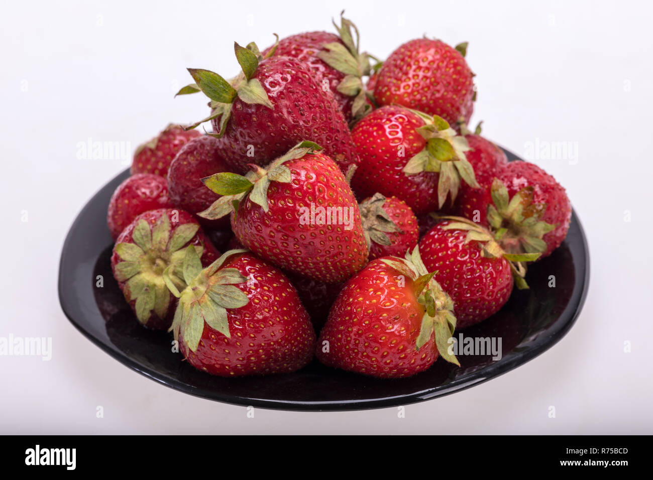 fresh ripe strawberries on black plate isolated on white background ...