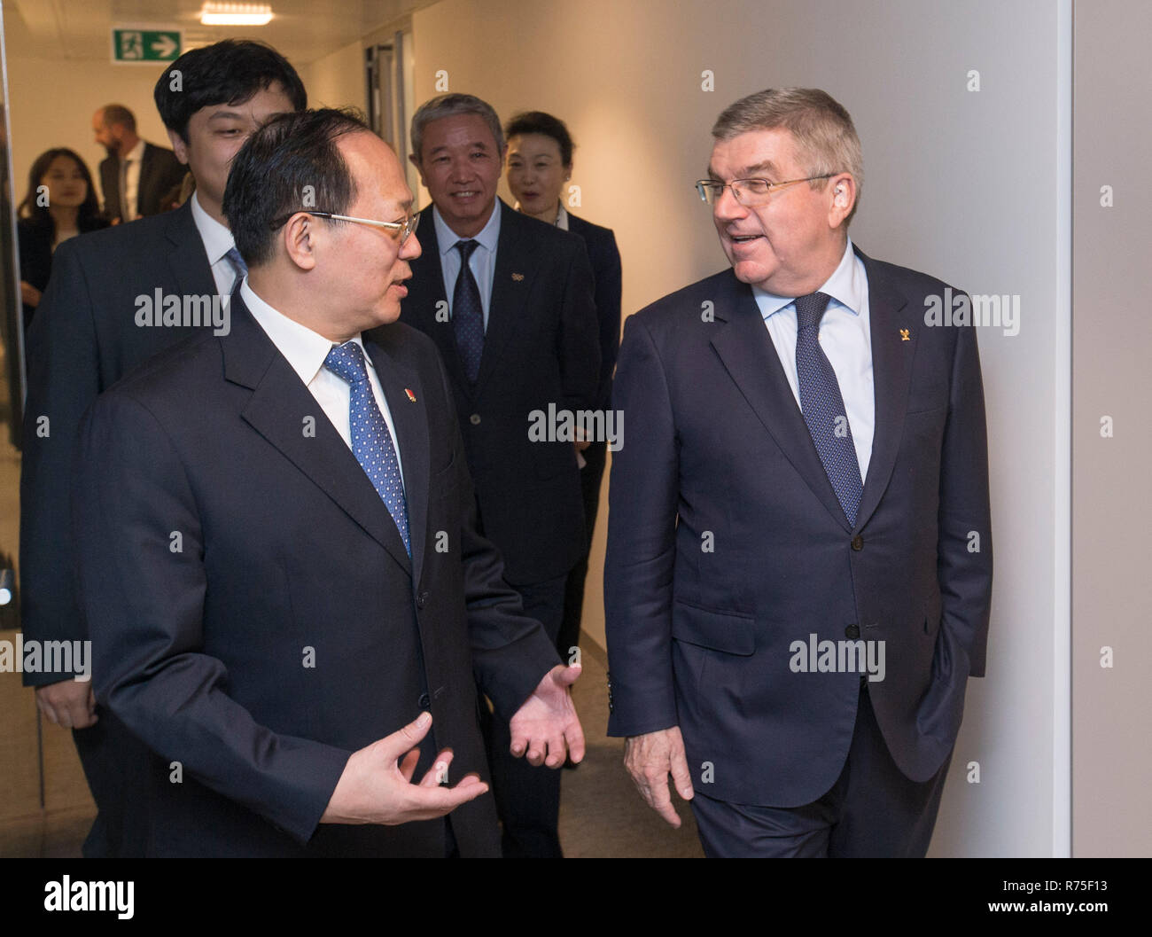 Lausanne, Switzerland. 7th Dec, 2018. International Olympic Committee (IOC) President Thomas Bach (R) is welcomed by Chinese Olympic Committee (COC) President Gou Zhongwen (L) during the opening ceremony of the COC Office in Lausanne, Switzerland, Dec. 7, 2018. The Chinese Olympic Committee (COC) inaugurated its office here on Friday to better communicate on a daily basis with the International Olympic Committee (IOC) and other international sports federations. Credit: Xu Jinquan/Xinhua/Alamy Live News Stock Photo