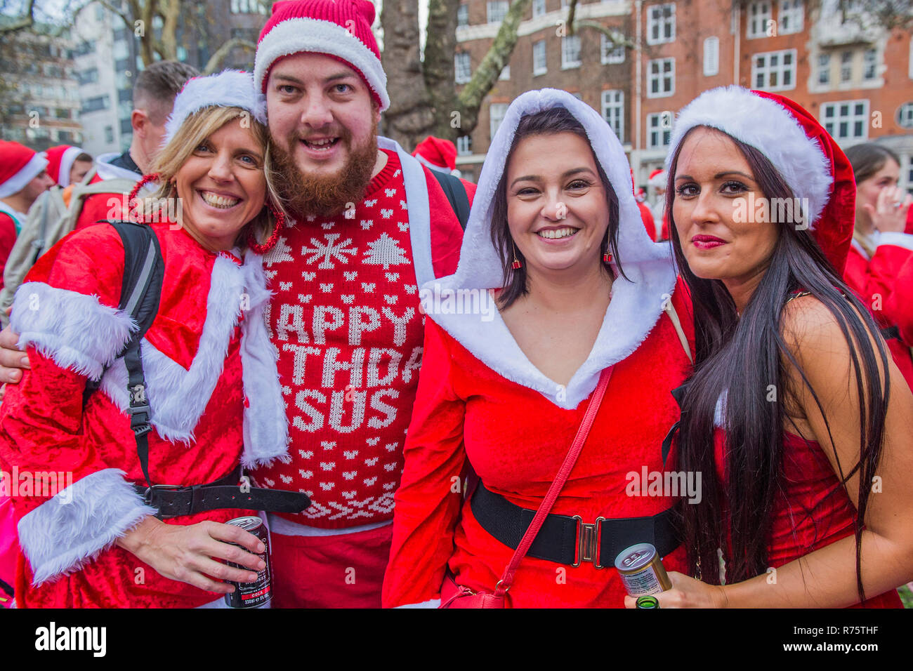 London, UK, 8th December 2018. Santas stop in the park in front of Euston Station for a respite and to drink some more. Santacon, a non-profit, non-political, non-religious, Christmas parade through London. Participants dress up in Santa suits and follow a leading Santa from several starting points ending up in Trafalgar Square. Credit: Guy Bell/Alamy Live News Stock Photo