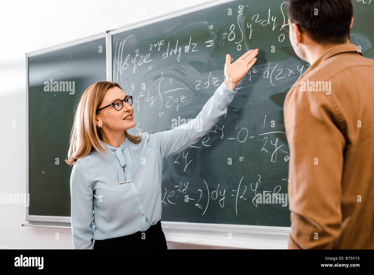 Female professor showing equations in classroom Stock Photo - Alamy