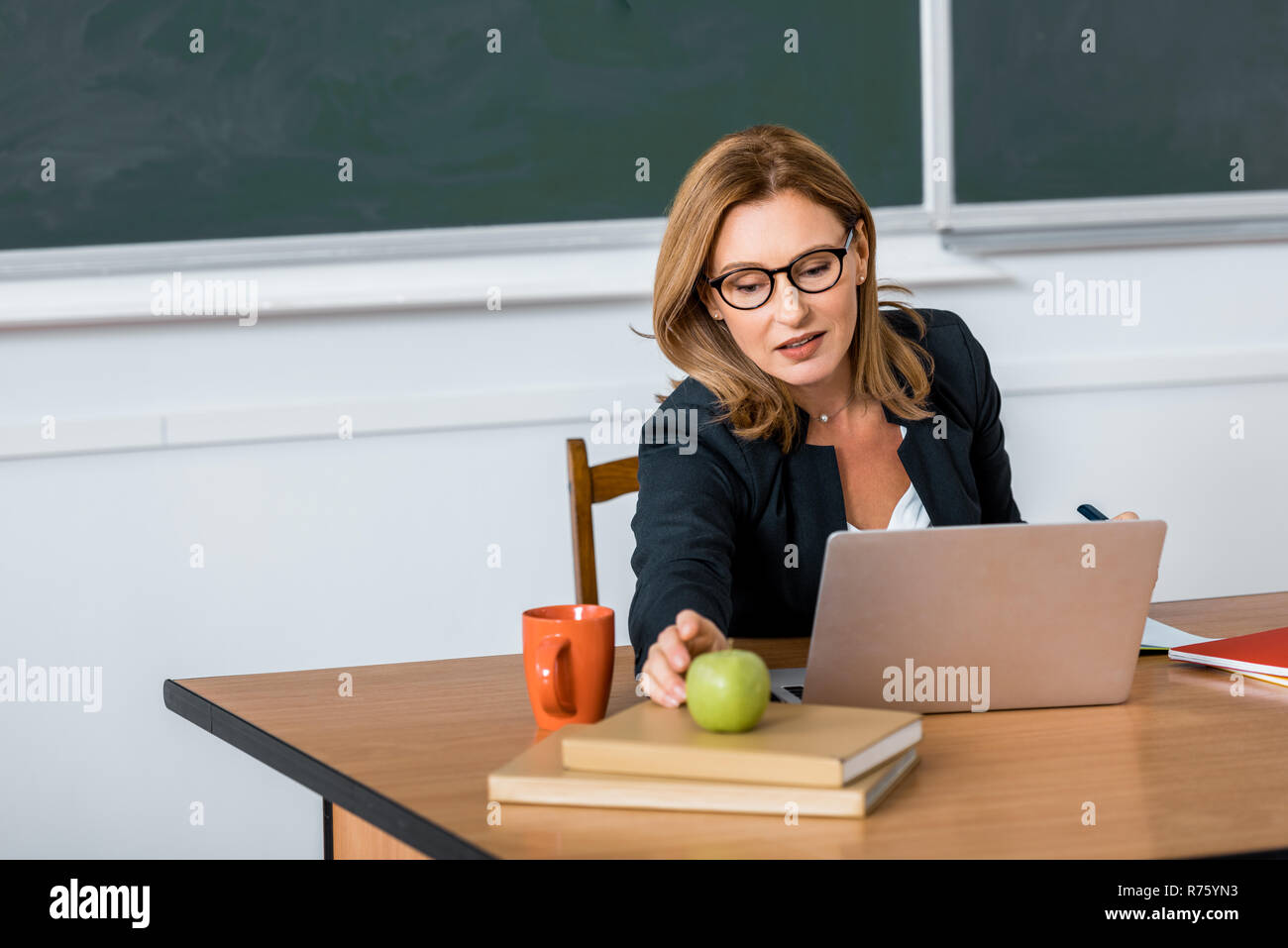 beautiful female teacher in glasses sitting at computer desk and ...