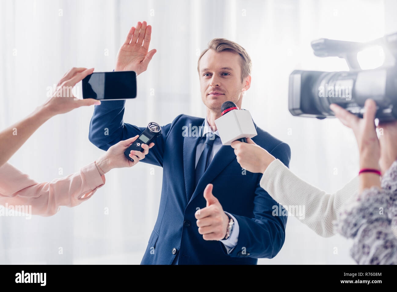 handsome businessman giving interview to journalists in office, waving ...