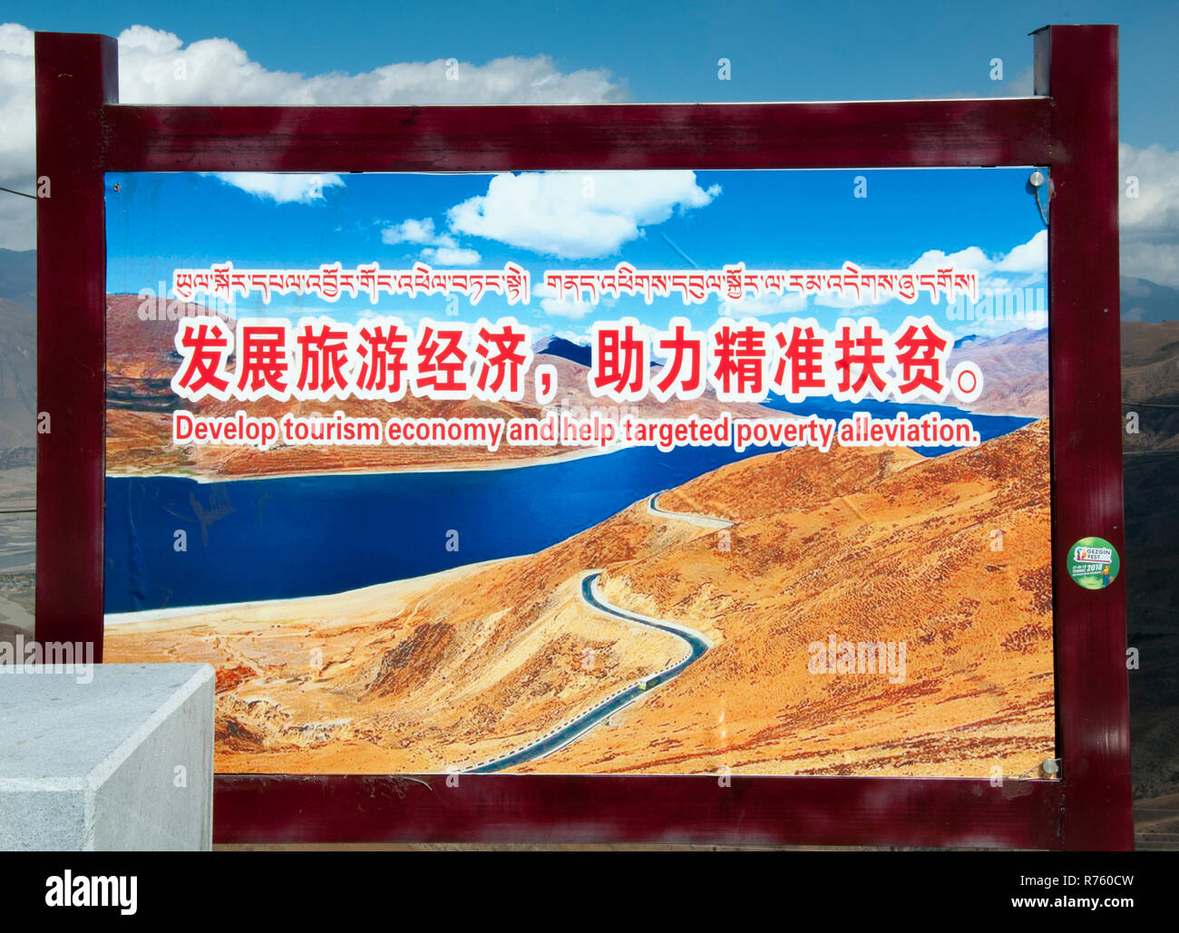 Propaganda billboard heralding development for tourism to alleviate poverty, at a rest area above Yamdrok Tso (Lake), Tibet, China Stock Photo