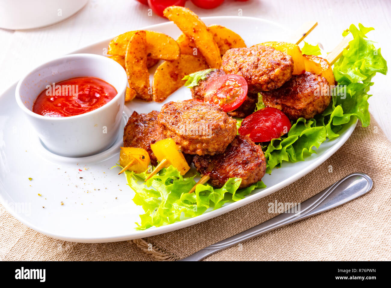 meatballs skewers of tomato,paprika and baked potato quarters Stock Photo