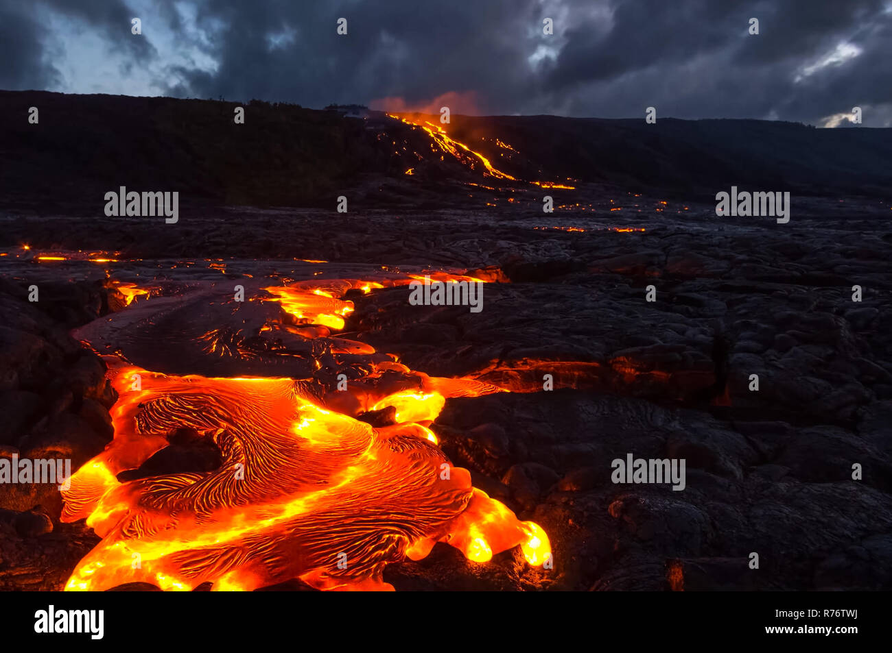 Pouring lava on the slope of the volcano. Volcanic eruption and magma. Stock Photo