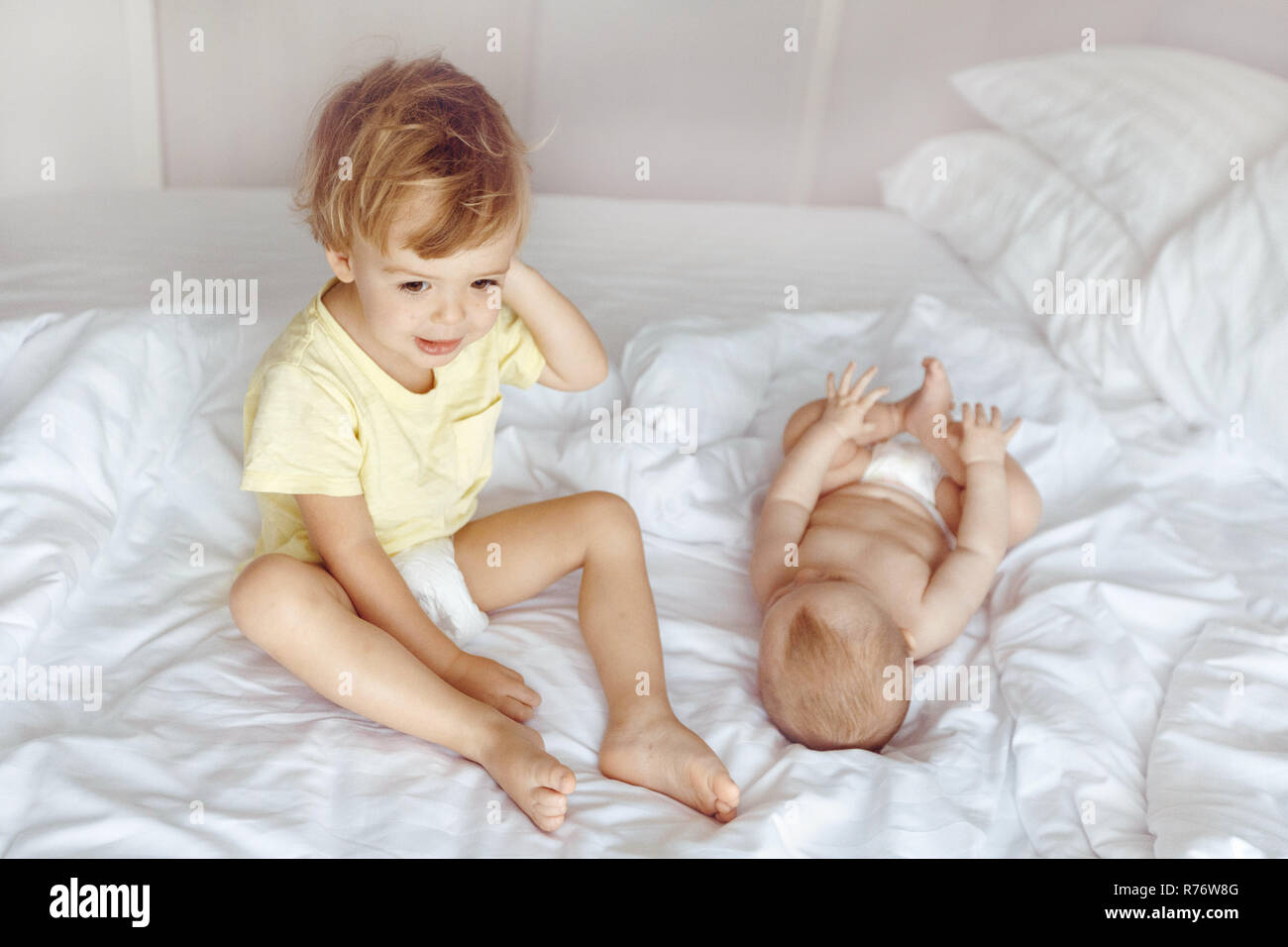 Kid sitting on bed near infant Stock Photo
