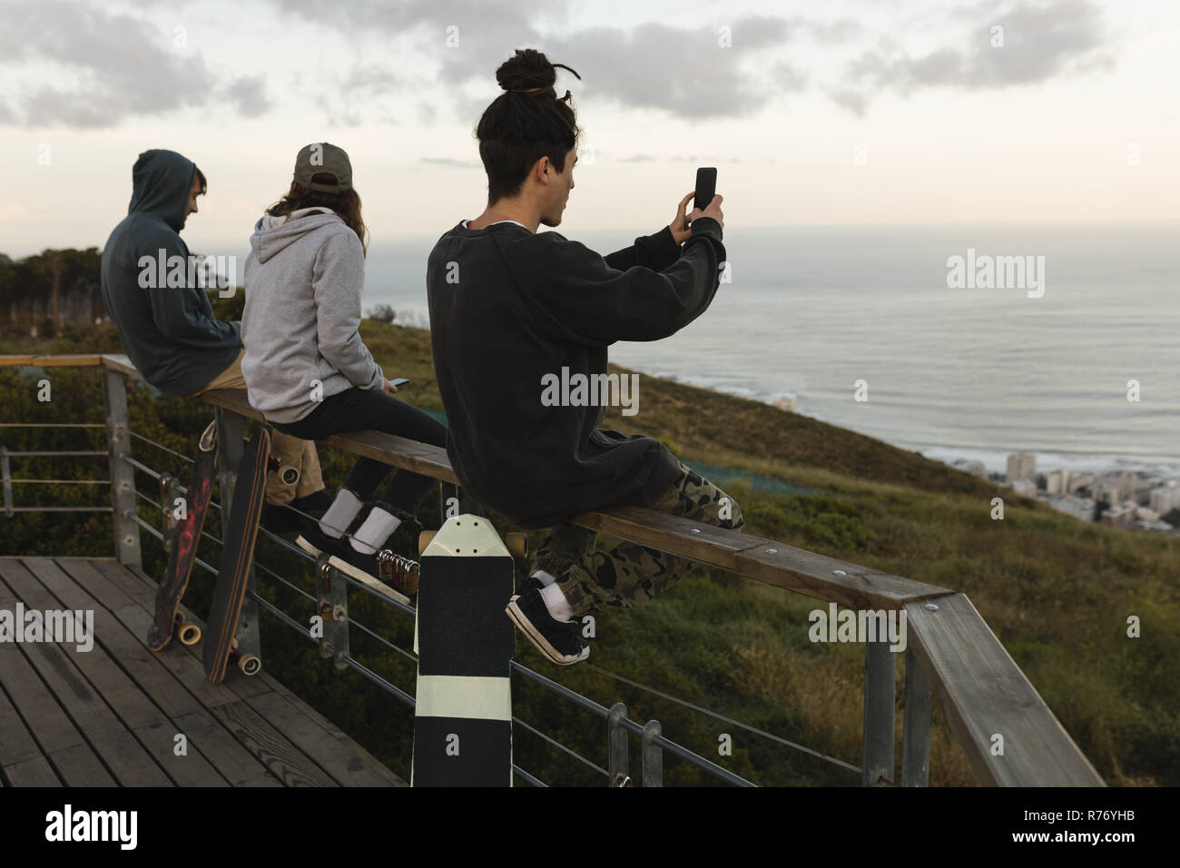 Skateboarders sitting on railing at observation point Stock Photo