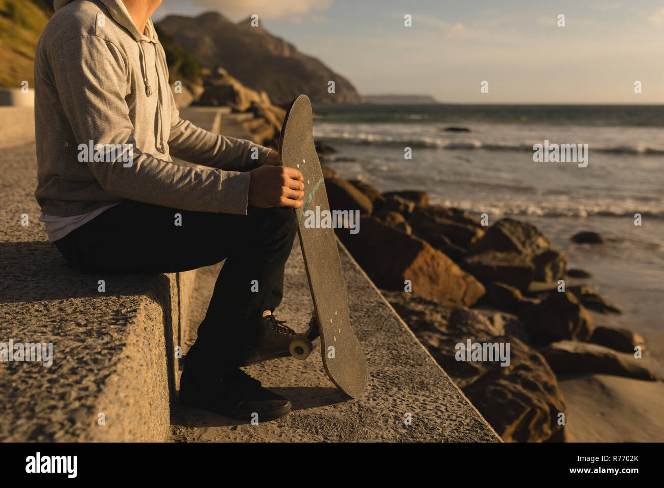 Man sitting with skateboard on the beach Stock Photo