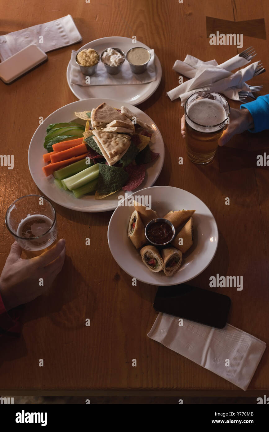 Friends holding beer glasses on the table in pub Stock Photo