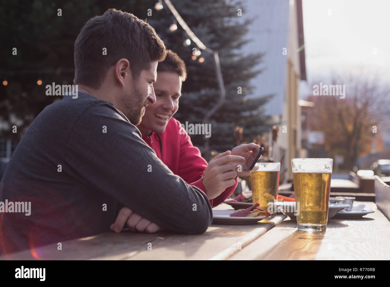 Friends discussing on mobile phone while having drinks Stock Photo