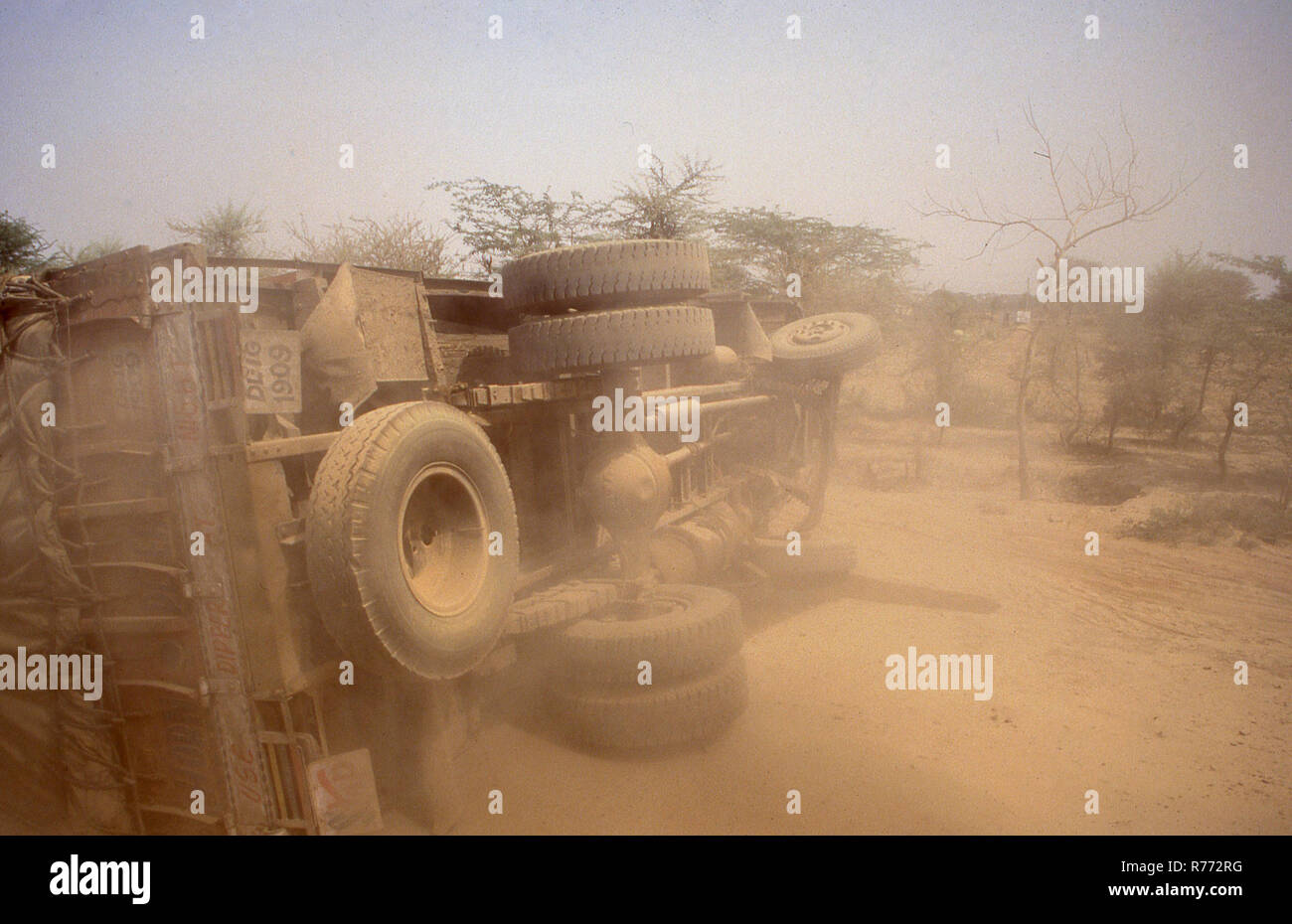 1970s, daytime and a crashed truck or goods vehicle in the African desert, upended and lying on its side on the sandy, arid terrain. Stock Photo
