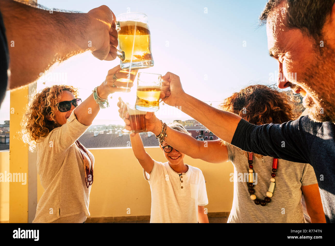 Group of people families and friends having fun together clinking with beers and orange juice