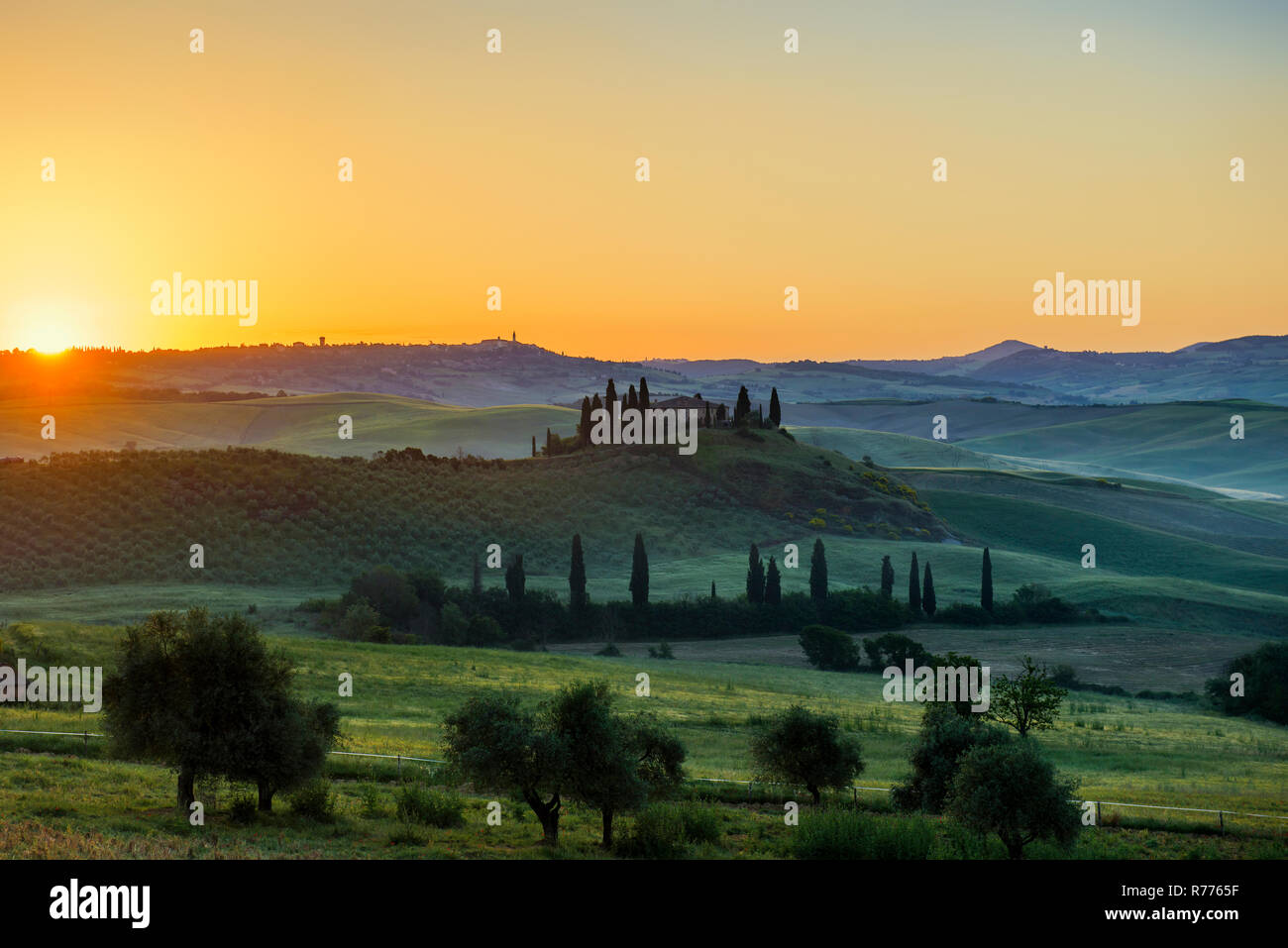 Sunrise landscape with farmhouse and cypress trees near San