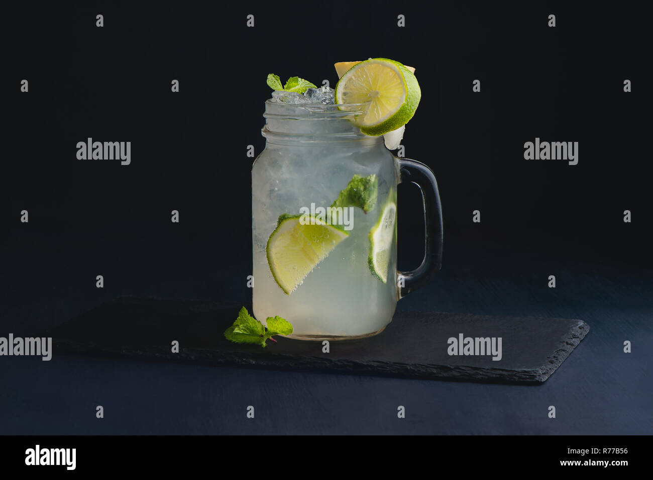 Ice cold classic lime lemonade in a vintage glass mason jar. Dark background with copy space for a menu. Stock Photo
