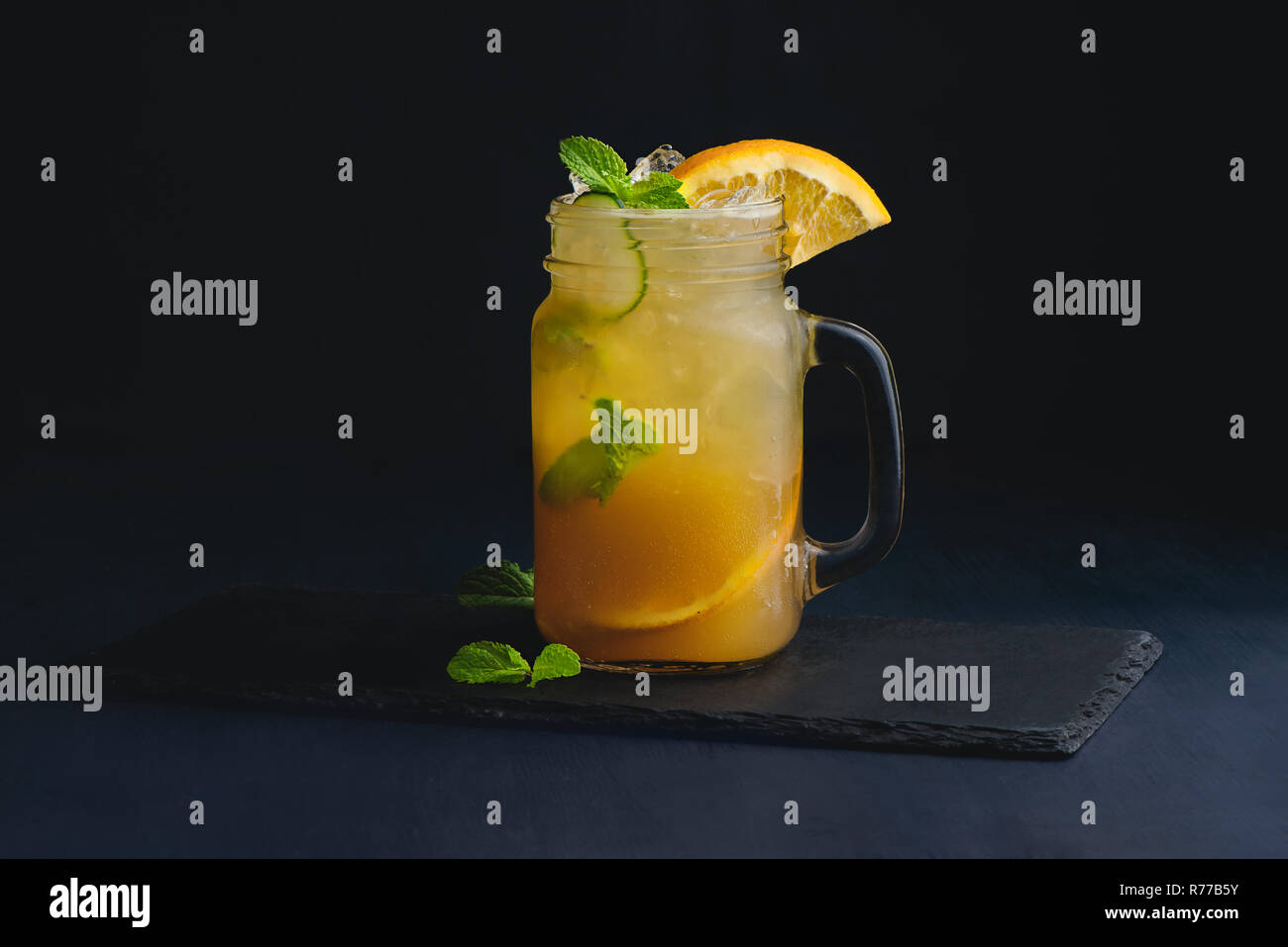 Ice cold citrus cocktail in a vintage glass mason jar. Dark background with copy space for a menu. Stock Photo