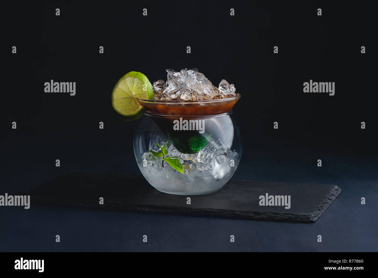 Espresso, mint and lime cocktail in a modern glass bowl. Coffee cold brew concept. Dark background with copy space for a menu. Stock Photo