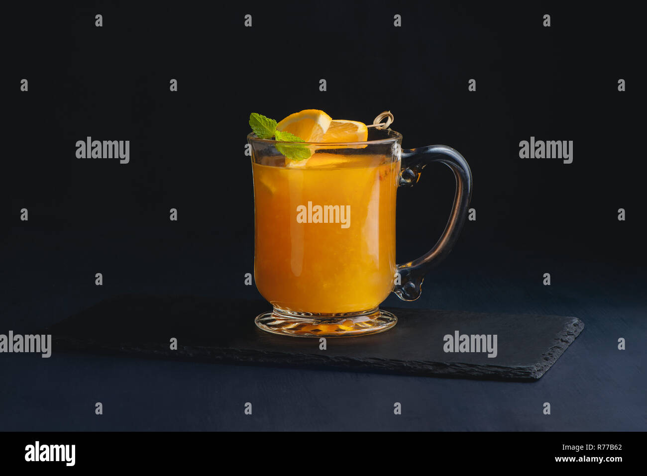 Fruit punch in a glass cup on a dark background with copy space for a menu. Orange, sea buckthorn or mango winter drink Stock Photo