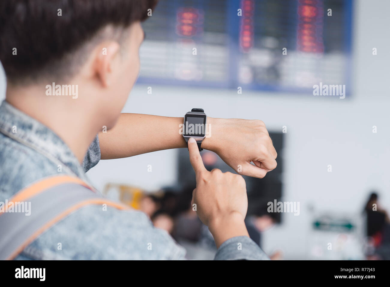 Passenger looking at the time on his wrist watch people at the airport